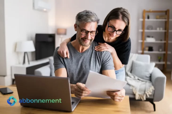 Pareja revisando papeles con una notebook en casa, charla sobre ahorro en pareja.