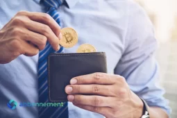 Uomo che inserisce monete Bitcoin in un portafoglio, simbolo dell’uso di un Criptovalute Wallet per gestire asset digitali.