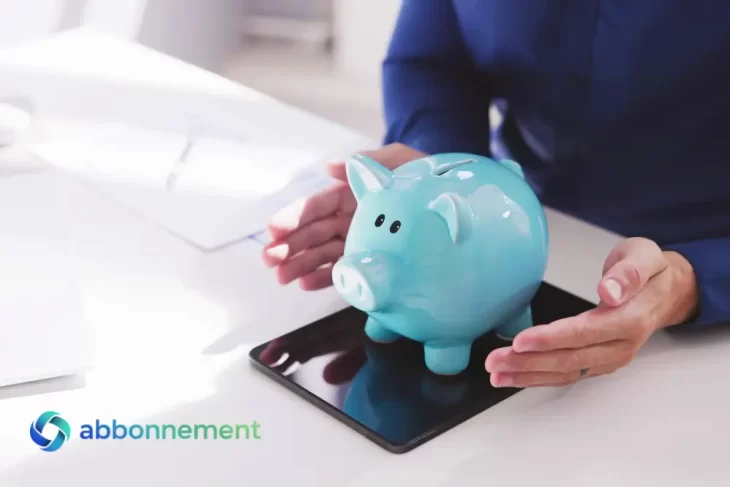 Alcancía azul sobre una tablet, manos alrededor, concepto de ingresos pasivos y ahorro.