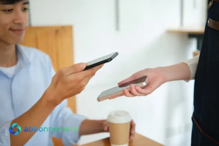 Cliente che paga un caffè tramite Pagamenti Digitali avvicinando lo smartphone al dispositivo del negoziante.