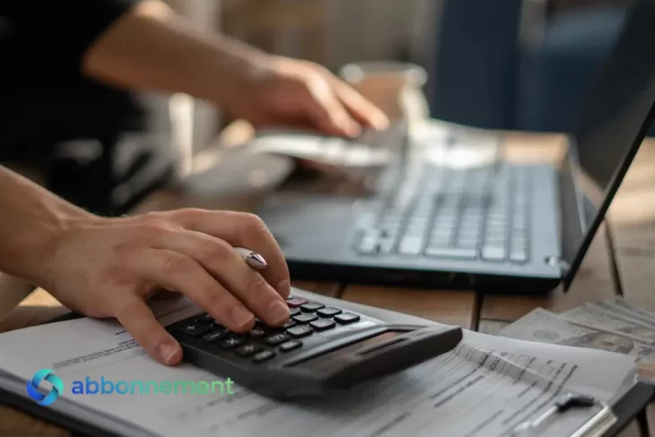 Calcolo di tasse e contributi con calcolatrice e laptop, simbolo della gestione della Partita IVA.
