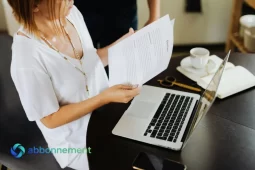 Lavoratrice che controlla documenti e computer, simbolo del TFR e della gestione della liquidazione.