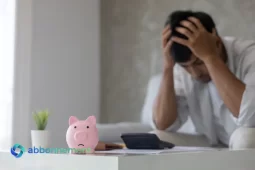 Persona preoccupata con documenti sul tavolo e salvadanaio, simbolo delle difficoltà finanziarie e del percorso per Uscire dai Debiti.