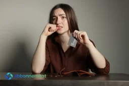 Donna preoccupata con carta di credito in mano, simbolo di errore finanziario e debiti.