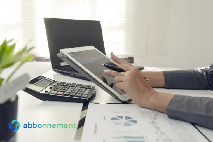 Persona che analizza dati di Finanza Incorporata su tablet accanto a calcolatrice e documenti.