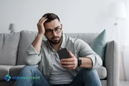 Uomo preoccupato che guarda il cellulare pensando alle conseguenze del debito pubblico sui risparmi.