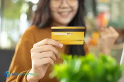Donna che mostra una carta di credito dorata, rappresentando il corretto utilizzo del credito al consumo.