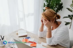 Mujer preocupada frente a una notebook, con facturas y calculadora, pensando cómo ordenar sus deudas personales.