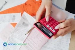 Manos usando una calculadora sobre recibos, para identificar gastos innecesarios en el presupuesto.