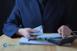 Persona contando billetes y usando calculadora frente a un gráfico, imagen sobre invertir con poco dinero y organizar finanzas.