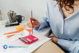 Persona armando un presupuesto mensual con calculadora, recibos y anotaciones sobre la mesa.