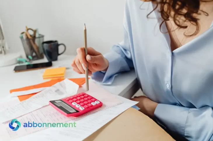 Persona usando una calculadora y anotando gastos en el escritorio, imagen ideal para explicar un presupuesto móvil mensual desde el celular.