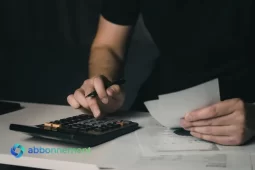 Persona usando calculadora y revisando papeles, imagen para explicar un presupuesto personal y controlar gastos.