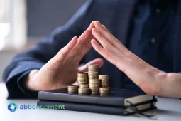 Manos en gesto de protección sobre monedas apiladas, idea de protegerse de la inflación y cuidar el ahorro.