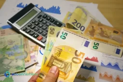 Persona che conta banconote in euro su un tavolo con grafici che mostrano come generare entrate extra dal proprio cellulare.