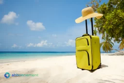 Maleta amarilla en la playa representando vacaciones económicas y planificación de viajes sin gastar de más.
