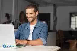 Uomo sorridente che usa un laptop, simbolo dell’accesso all’Internet Sociale.