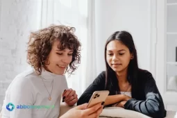 Due donne che guardano uno smartphone insieme, simbolo di informazione e accesso all’Assegno di Inclusione.