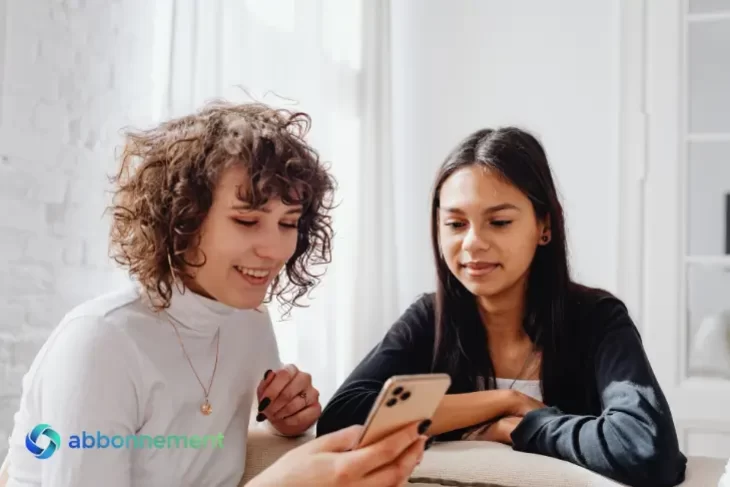 Due donne che guardano uno smartphone insieme, simbolo di informazione e accesso all’Assegno di Inclusione.
