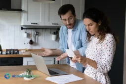Coppia in cucina che controlla bollette e documenti per capire come uscire dai debiti.