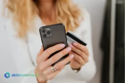 Persona con smartphone e carta di credito, rappresentazione di un cattivo pagatore e delle difficoltà di accesso al credito.