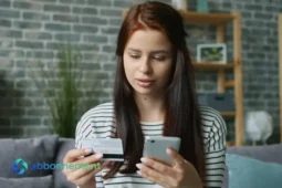 Donna controlla spese su smartphone con carta di credito