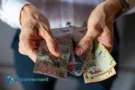 Manos sosteniendo billetes argentinos, representando los pesos que sobran y cómo cuidarlos.