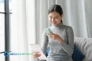 Donna controlla la bolleta della luce e del gas sullo smartphone sorridendo