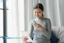 Donna controlla la bolleta della luce e del gas sullo smartphone sorridendo