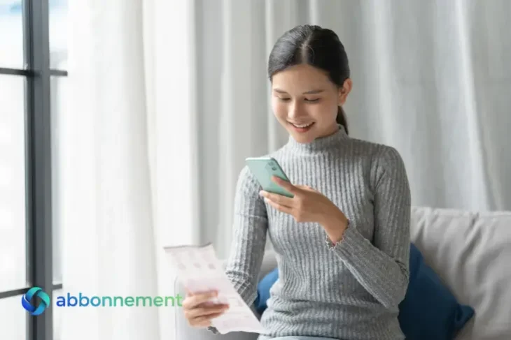 Donna controlla la bolleta della luce e del gas sullo smartphone sorridendo