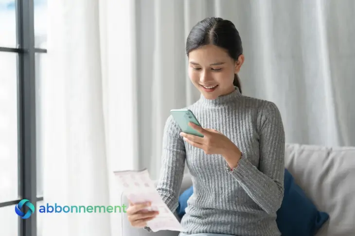 Donna controlla la bolleta della luce e del gas sullo smartphone sorridendo