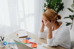 Donna preoccupata al tavolo mentre cerca soluzioni su come estinguere i debiti.