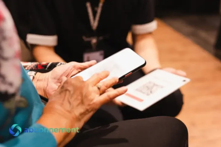 Una persona anziana scansiona un codice QR su un tablet tenuto da un dipendente, un'azione comune che richiede attenzione contro la truffa qr code.